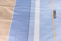 Close-up of a blue fabric with a zipper and label on a beige background