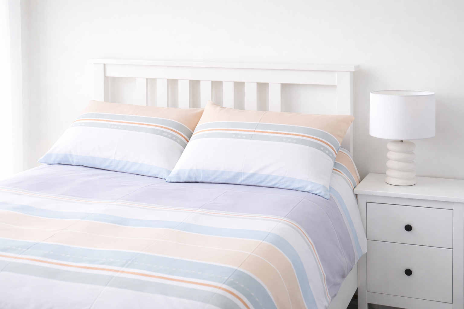 Bed with striped bedding and a nightstand in a bedroom setting