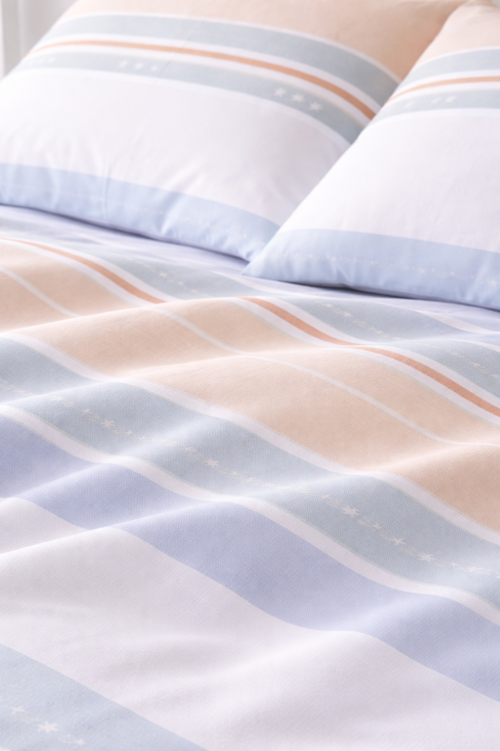 Striped bedding with light blue and beige colors on a bed.