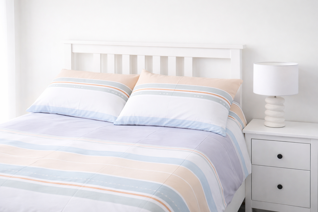 Bed with striped bedding and a nightstand in a bedroom setting